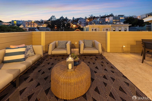 patio terrace at dusk featuring a balcony and an outdoor living space