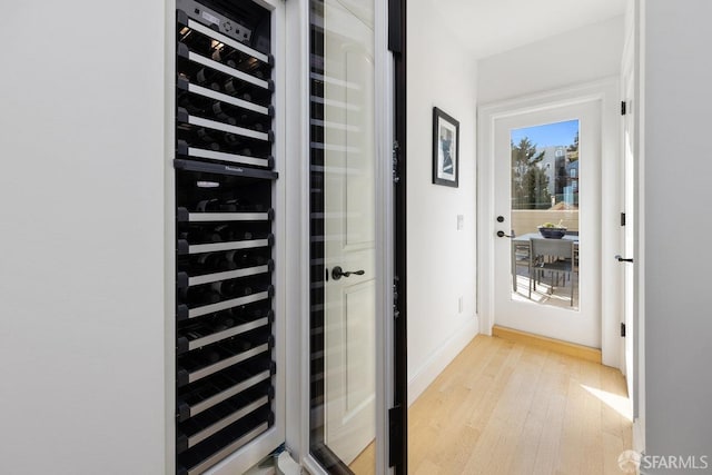 doorway to outside with wine cooler and light hardwood / wood-style flooring