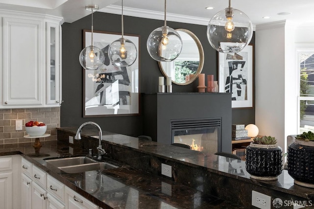 kitchen with dark stone countertops, decorative light fixtures, sink, and white cabinets