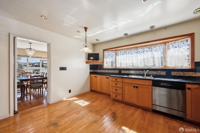 kitchen featuring pendant lighting, dark countertops, light wood-style floors, a sink, and dishwasher