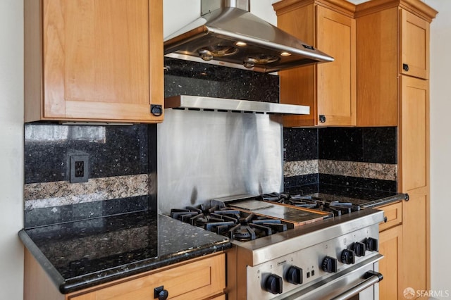 kitchen featuring high end stainless steel range oven, dark stone counters, extractor fan, and backsplash