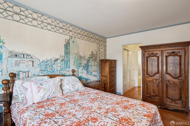 bedroom with ornamental molding and wood finished floors