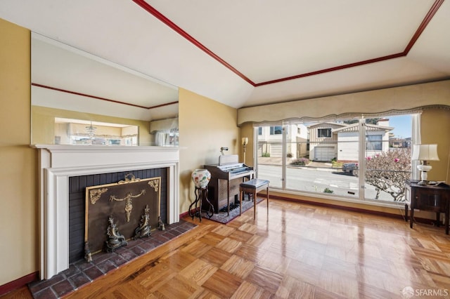 living room with vaulted ceiling, ornamental molding, a tiled fireplace, and baseboards