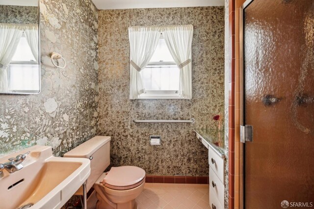 full bathroom with toilet, wallpapered walls, a shower stall, and a sink