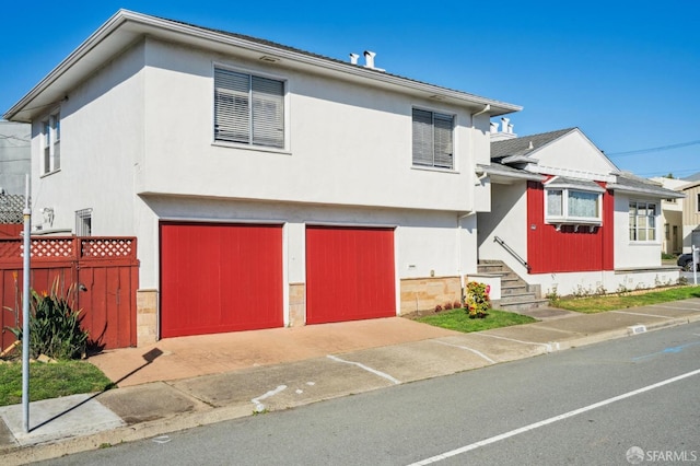 view of front of house with an attached garage, fence, and stucco siding