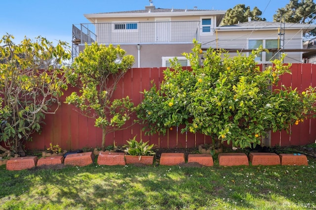 view of yard featuring fence and a balcony