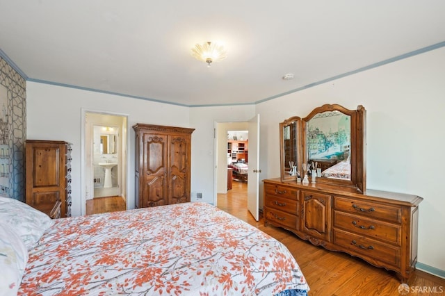 bedroom with ensuite bath and light wood finished floors