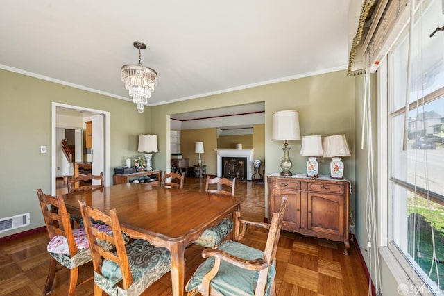 dining area featuring a fireplace, visible vents, ornamental molding, a chandelier, and baseboards