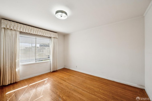 spare room with baseboards and wood finished floors