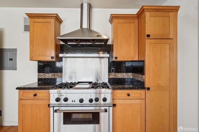 kitchen featuring tasteful backsplash, high end stainless steel range oven, dark stone countertops, electric panel, and wall chimney exhaust hood