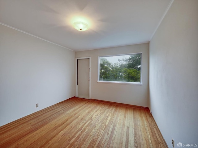 spare room featuring crown molding and light hardwood / wood-style floors