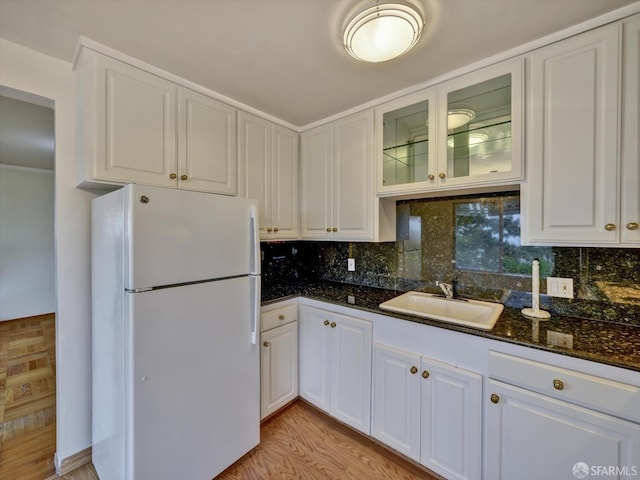 kitchen featuring dark stone countertops, sink, white cabinets, and white fridge