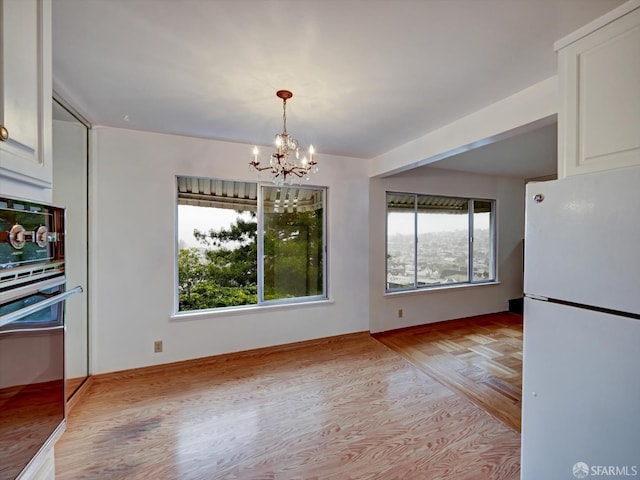 unfurnished dining area with light wood-type flooring and an inviting chandelier