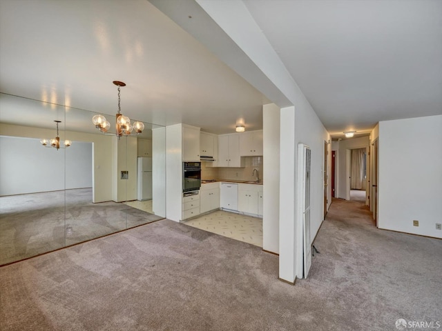 kitchen featuring decorative light fixtures, white cabinetry, sink, light colored carpet, and white appliances