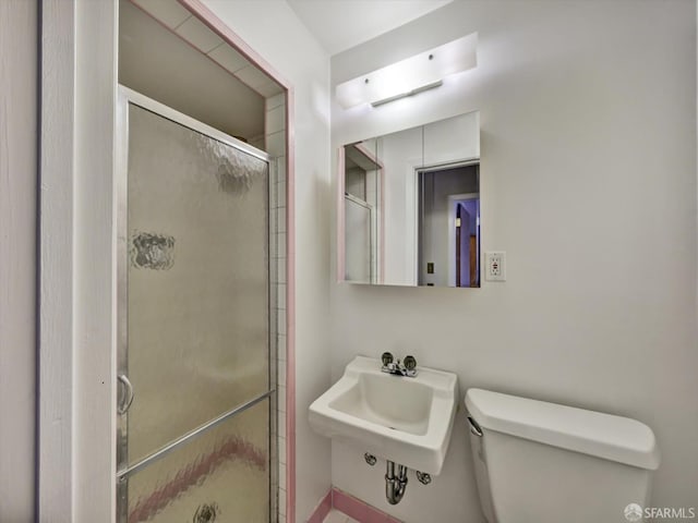 bathroom featuring toilet, an enclosed shower, and sink