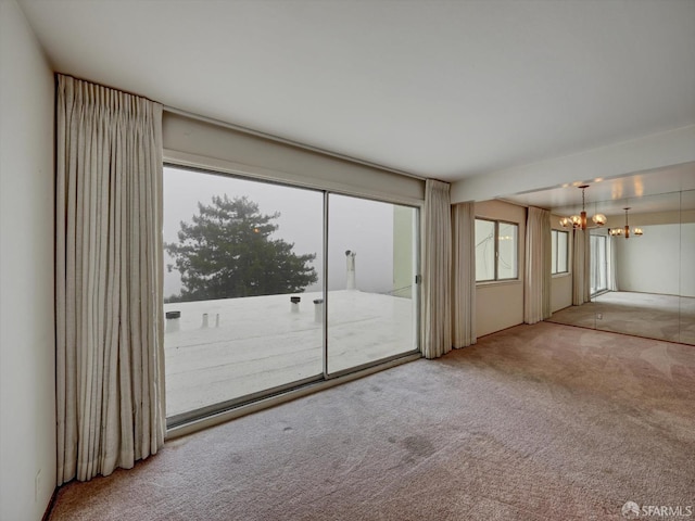 carpeted spare room with a notable chandelier