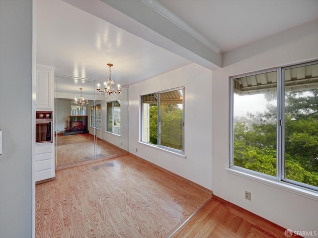 unfurnished living room featuring an inviting chandelier and light hardwood / wood-style floors