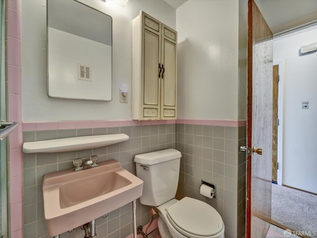 bathroom with toilet, sink, and tile walls