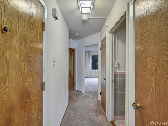 corridor with light colored carpet and tile walls