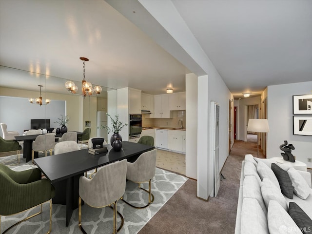 dining space featuring an inviting chandelier, sink, and light colored carpet