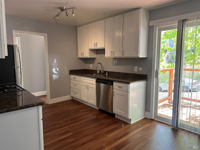 kitchen with stainless steel appliances, dark hardwood / wood-style flooring, white cabinetry, dark stone countertops, and sink