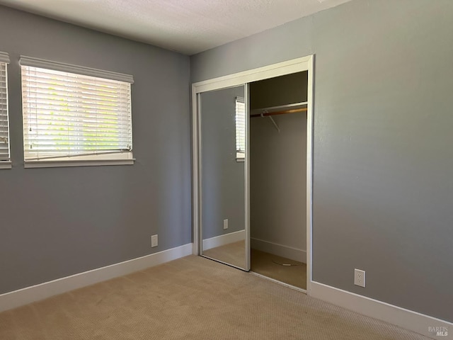 unfurnished bedroom featuring light colored carpet and a closet