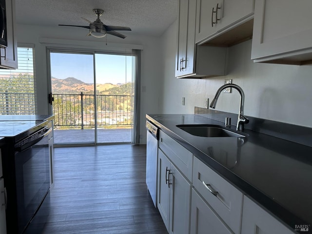 kitchen with a textured ceiling, a mountain view, dishwashing machine, black range with electric stovetop, and sink