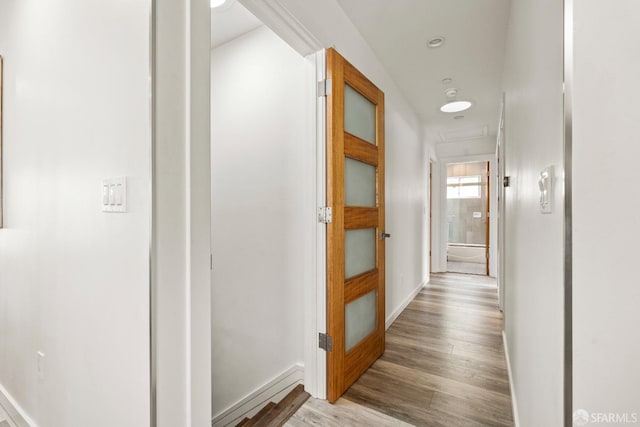 corridor with light wood-style flooring and baseboards