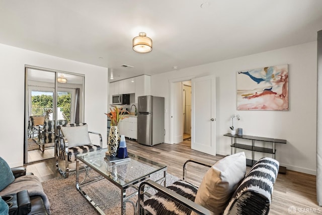 living area featuring light wood-type flooring and baseboards