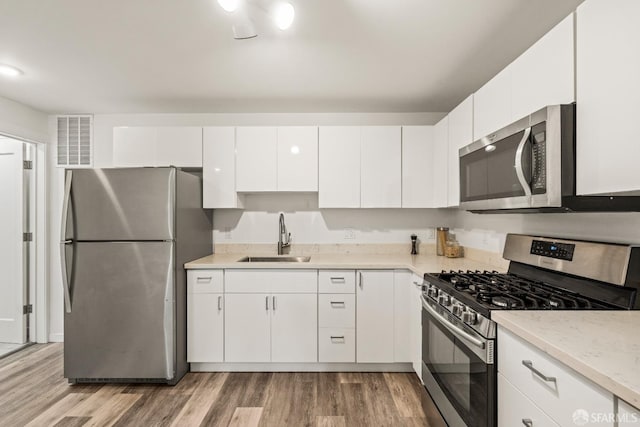 kitchen featuring light wood finished floors, visible vents, appliances with stainless steel finishes, and a sink