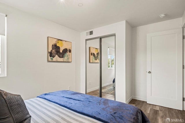 bedroom featuring a closet, visible vents, baseboards, and wood finished floors