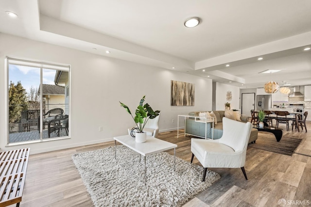 living area featuring light wood finished floors, a raised ceiling, and recessed lighting