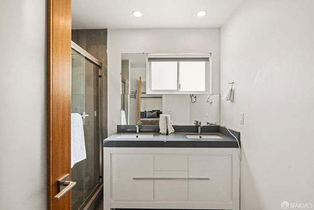 bathroom featuring a stall shower, a sink, recessed lighting, and double vanity