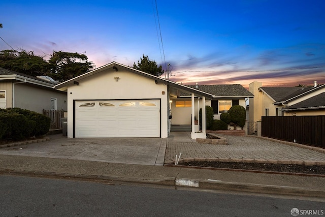 ranch-style house with concrete driveway, fence, an attached garage, and stucco siding