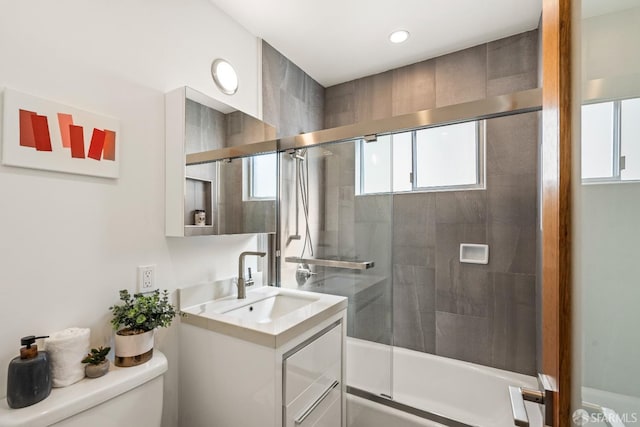 bathroom with toilet, shower / bath combination with glass door, and vanity