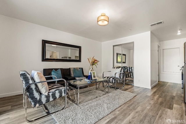 living area with visible vents, baseboards, and wood finished floors