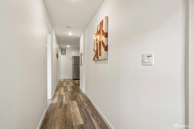 hall with dark wood-style flooring, visible vents, and baseboards