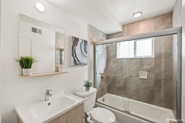 bathroom with toilet, enclosed tub / shower combo, visible vents, and vanity