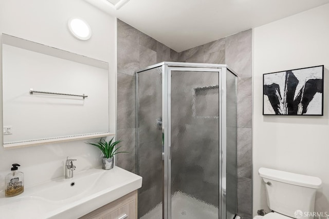 bathroom featuring toilet, a shower stall, and vanity