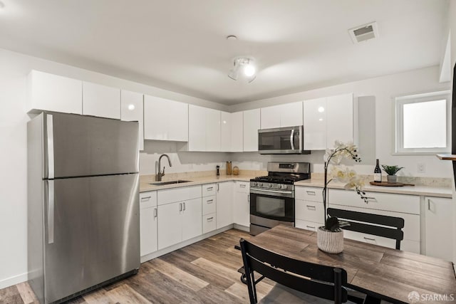 kitchen featuring stainless steel appliances, visible vents, a sink, and white cabinetry