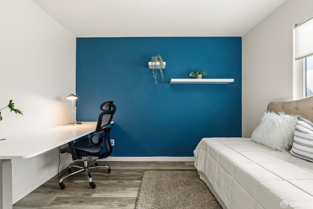 bedroom with an accent wall, baseboards, and wood finished floors