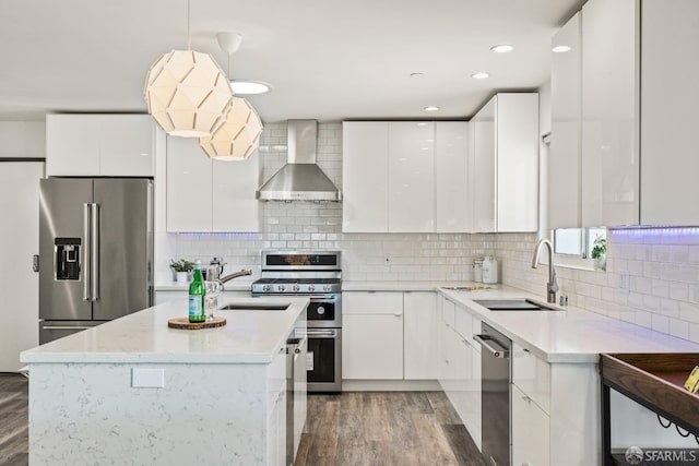 kitchen featuring stainless steel appliances, a sink, white cabinets, wall chimney exhaust hood, and modern cabinets