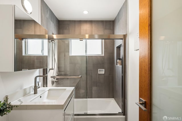 bathroom with a healthy amount of sunlight, a shower stall, and vanity