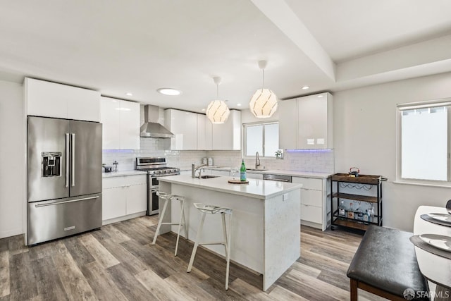 kitchen featuring white cabinetry, wall chimney exhaust hood, appliances with stainless steel finishes, and a sink