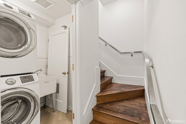 washroom with laundry area, stacked washing maching and dryer, and visible vents