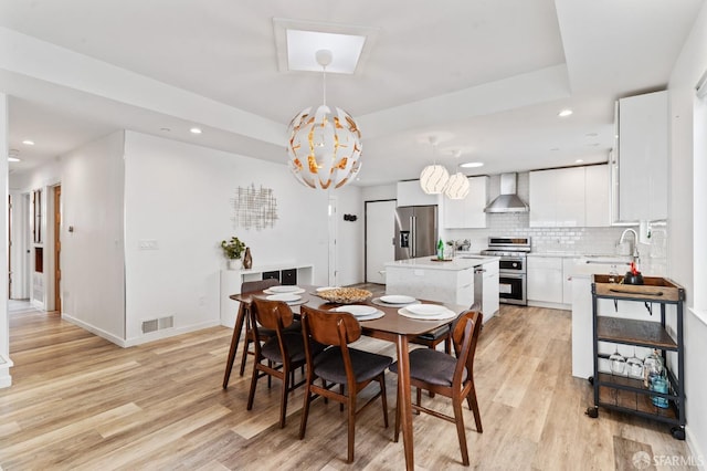 dining area featuring a tray ceiling, recessed lighting, visible vents, and light wood-style floors