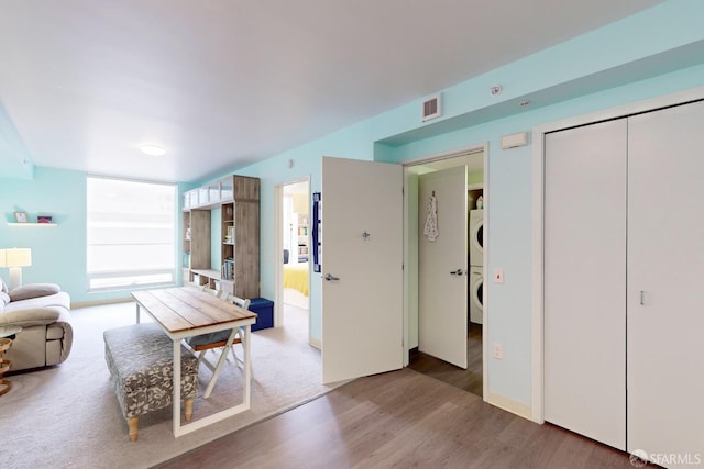 interior space with stacked washer and clothes dryer and hardwood / wood-style flooring