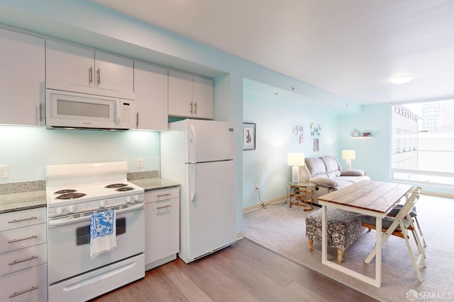 kitchen featuring light stone countertops, white appliances, and light hardwood / wood-style floors