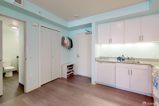 kitchen with white dishwasher, light hardwood / wood-style flooring, sink, and white cabinets