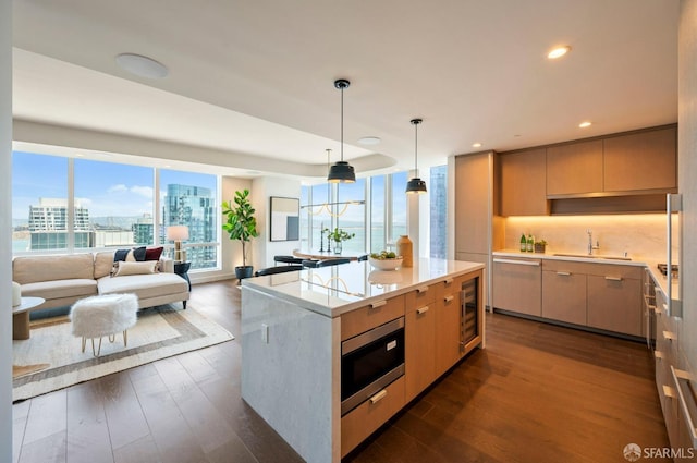 kitchen featuring appliances with stainless steel finishes, light brown cabinets, dark hardwood / wood-style flooring, sink, and hanging light fixtures